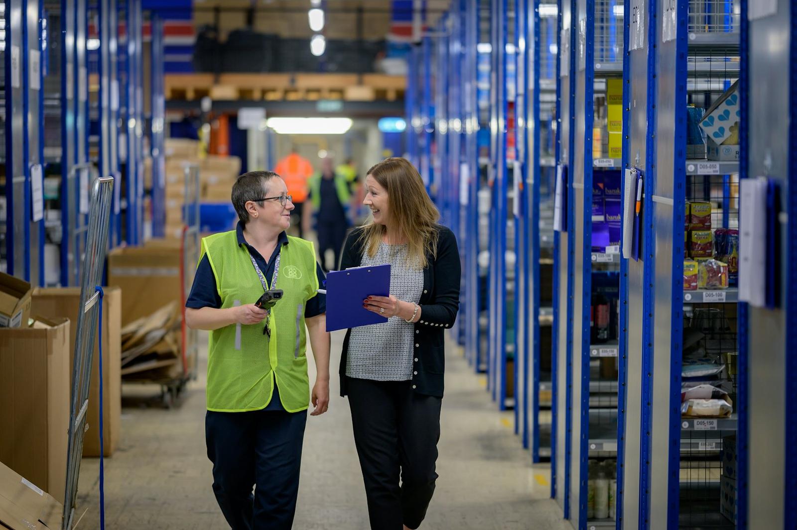 Dos personas revisan inventario en un pasillo de almacén